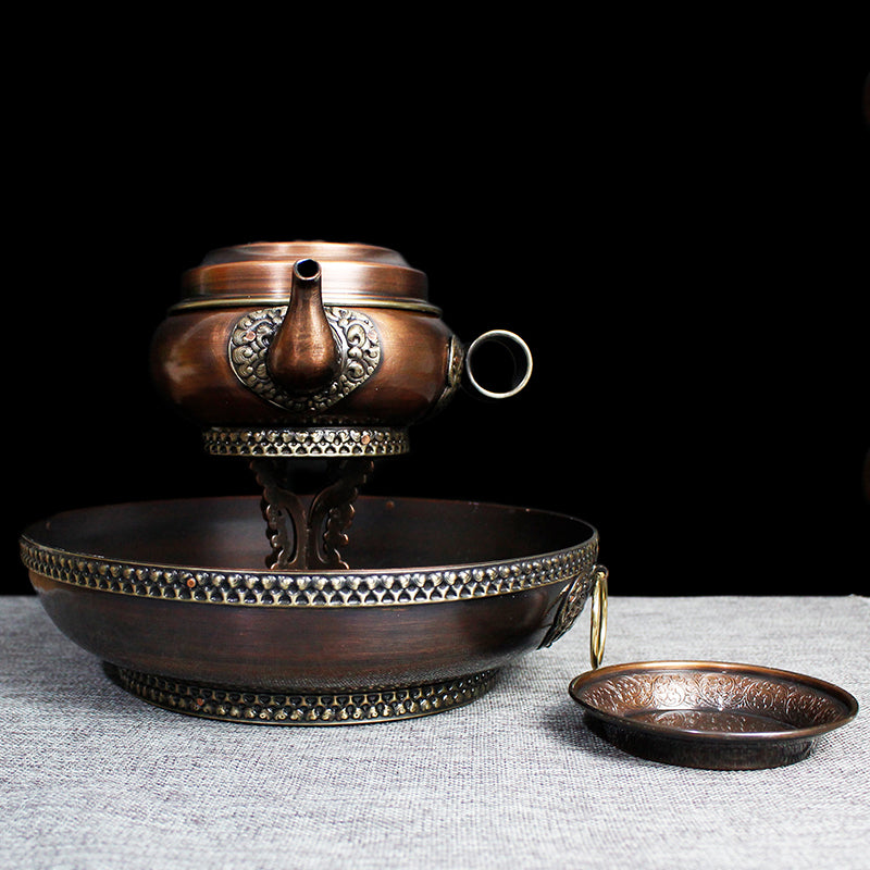 A Nepalese fine copper chutor water offering set featuring a large copper pot with intricate patterns and floral motifs, a smaller copper plate, and a detachable copper stand.